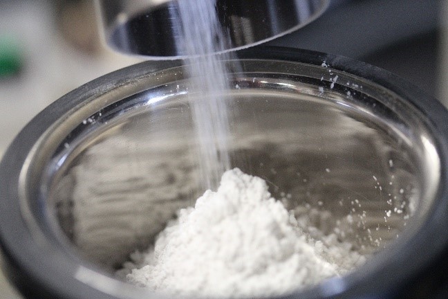 photography of a white powder falling into the granuheap instrument made by granutools